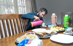 a man standing at a table drinking from a cup at ArushaLand homestay in Arusha