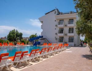 a swimming pool with orange chairs and a building at Side Sunset Hotel in Side