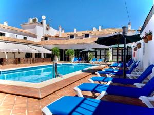 una piscina con tumbonas azules y un hotel en Hotel Tugasa Sierra y Cal, en Olvera