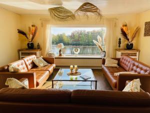 a living room with leather couches and a large window at Ferienhaus Peppi - Haus am See in Güster