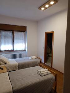 - une chambre avec 2 lits, une fenêtre et un miroir dans l'établissement Albergo San Giorgio, à Baselga di Pinè
