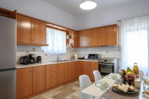 a kitchen with wooden cabinets and a table with food on it at Villa Vigla Keratokampos in Keratokampos