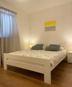 ein weißes Bett in einem Zimmer mit Fenster in der Unterkunft Apartman Marija in Posedarje