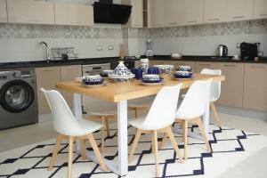 a kitchen with a wooden table and white chairs at la villa farniente de sidi bou said in Sidi Bou Saïd
