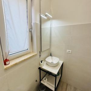 a white bathroom with a sink and a window at La casa del nonno - Villapiana in Villapiana