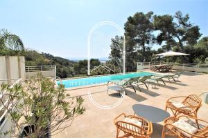 una piscina con mesas y sillas junto a una piscina en Villa Mont des Oiseaux-Piscine Chauffée Clim Vue Mer Wifi 4 chambres By HC, en Hyères