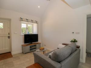 ein Wohnzimmer mit einem Sofa und einem Flachbild-TV in der Unterkunft The Grooms Flat in Malmesbury