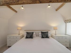 ein Schlafzimmer mit einem weißen Bett und zwei Nachttischen in der Unterkunft The Grooms Flat in Malmesbury
