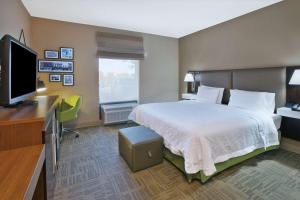 a hotel room with a bed and a flat screen tv at Hampton Inn Commerce/Novi in Walled Lake