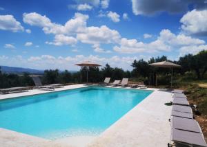 einen Pool mit Stühlen und Sonnenschirmen in der Unterkunft Agriturismo Villa Val D'Olivi in Capodacqua