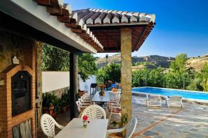 a patio with tables and chairs and a swimming pool at Casa Rural Las Huertas de Roque in Monachil