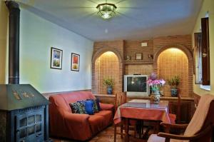 uma sala de estar com um sofá, uma televisão e uma mesa em Casa Rural Las Huertas de Roque em Monachil