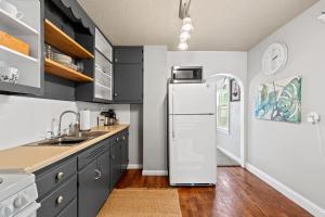 een keuken met zwarte kasten en een witte koelkast bij Modern meets cozy - minutes from downtown. in Rapid City