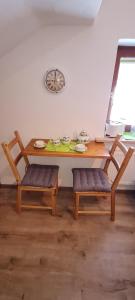 stół z dwoma ławkami i zegarem na ścianie w obiekcie Haus Bergblick w mieście Mittenwald +2 zdjęcia
