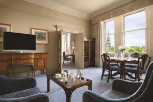 a living room with a table and a television at The Caledonian Edinburgh, Curio Collection by Hilton in Edinburgh
