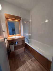 a bathroom with a sink and a tub and a mirror at Charmant logement dans résidence in Super Besse
