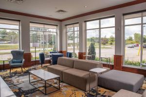 a living room with a couch and chairs and windows at Hilton Garden Inn Erie in Erie