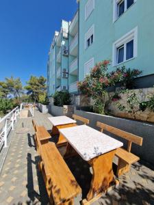 two wooden tables and benches in front of a building at Apartment Iva in Trogir