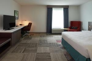 a hotel room with a bed and a desk and a television at Hilton Garden Inn Evansville in Evansville