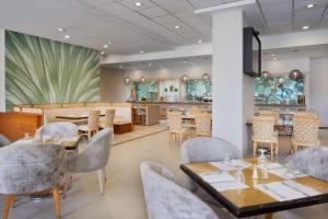 a restaurant with tables and chairs and a kitchen at Hilton Hasbrouck Heights-Meadowlands in Hasbrouck Heights