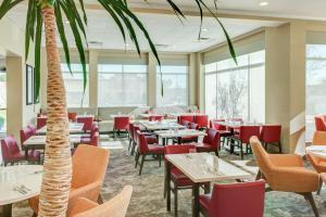 ein Restaurant mit Tischen, Stühlen und einer Palme in der Unterkunft Hilton Garden Inn Lakewood in Lakewood