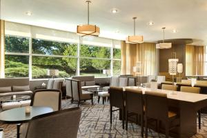 a restaurant with tables and chairs and windows at Hilton Meadowlands in East Rutherford