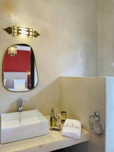 La salle de bains est pourvue d'un lavabo blanc et d'un miroir. dans l'établissement Riad Deha & Spa, à Marrakech