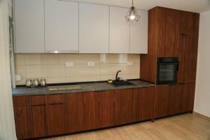 une cuisine avec des armoires en bois, un évier et un micro-ondes dans l'établissement Lakeside Serenity, à Žabljak
