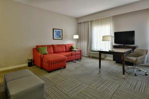 a living room with a red couch and a desk at Hampton Inn & Suites Fredericksburg in Fredericksburg