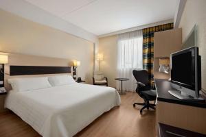 a hotel room with a bed and a flat screen tv at Hilton Garden Inn Rome Airport in Fiumicino