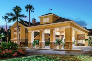 a large yellow building with palm trees in the background at Homewood Suites by Hilton Fort Myers in Fort Myers