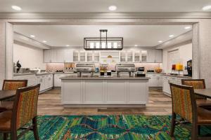 a large kitchen with white cabinets and a table and chairs at Homewood Suites by Hilton Fort Myers in Fort Myers