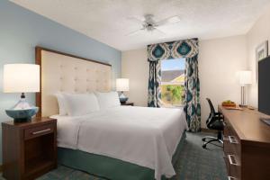 a bedroom with a bed and a desk and a window at Homewood Suites by Hilton Fort Myers in Fort Myers