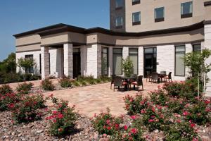 a building with a patio with chairs and flowers at Hilton Garden Inn Ft Worth Alliance Airport in Roanoke