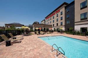 a hotel with a swimming pool in front of a building at Hilton Garden Inn Ft Worth Alliance Airport in Roanoke