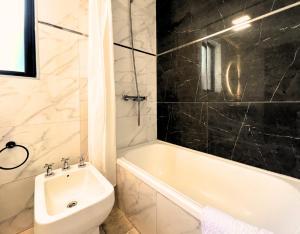 ein Badezimmer mit einer weißen Badewanne, einem WC und einem Waschbecken in der Unterkunft Parque Pueyrredon IV in Mendoza