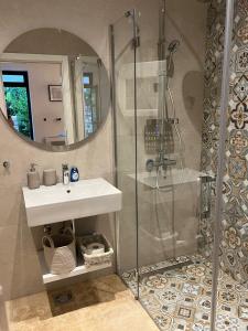uma casa de banho com um chuveiro, um lavatório e um espelho. em ROSE Downtown em Podgorica