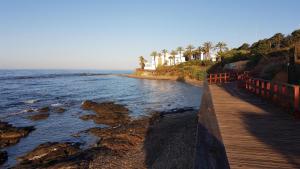 uma passagem de madeira junto ao oceano com palmeiras em Beach Apartment La Cala de Mijas em La Cala de Mijas