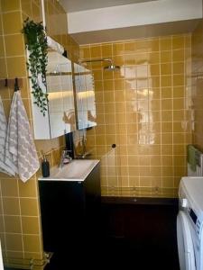 a yellow tiled bathroom with a sink and a mirror at Studio Kuopion kattojen yllä in Kuopio
