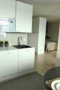 a white kitchen with a sink and a bedroom at Studio Kuopion kattojen yllä in Kuopio