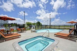 a swimming pool with chairs and a table and umbrella at Hilton Garden Inn Gulfport - Biloxi Airport in Gulfport