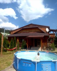 a woman in a pool in front of a house at Лісова пісня in Verkhovyna
