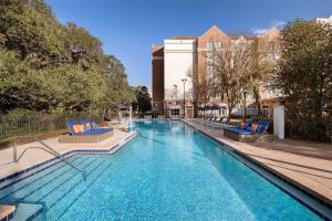 a large swimming pool with blue chairs and a building at Hilton University of Florida Conference Center Gainesville in Gainesville