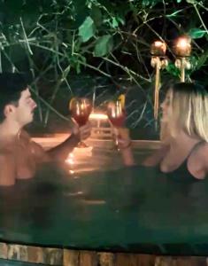 un hombre y una mujer sosteniendo copas de vino en una piscina en La Casita- imawi en Belén de Escobar