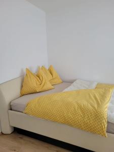 a bed with yellow blankets and pillows on it at Villa LOE in Villach