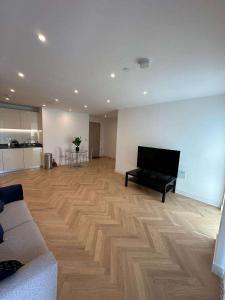 a living room with a piano on a wooden floor at Spacious one bedroom luxury apartment in Kidbrooke Greenwich in London