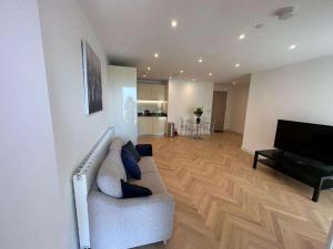 ein Wohnzimmer mit einem Sofa und einem Flachbild-TV in der Unterkunft Spacious one bedroom luxury apartment in Kidbrooke Greenwich in London
