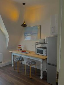 a kitchen with a table with a microwave and a refrigerator at City Apartment, Ferienwohnung 3 ZKDB, Balkon, Dachgeschoss, nähe Düsseldorf in Krefeld