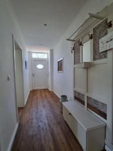 a hallway with a white room with a bench and a door at Ferienhaus Am Fehntjer Tief in Emden