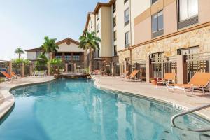 a swimming pool with chairs and a building at Hampton Inn and Suites Houston Clear Lake NASA in Webster